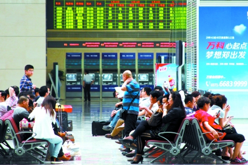 候車大廳溫度很高，一名乘客一手扇風、一手擦汗