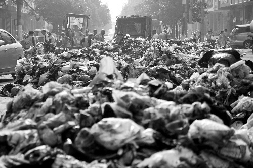 垃圾堆滿整個(gè)路口，環(huán)衛(wèi)工人們正在清理